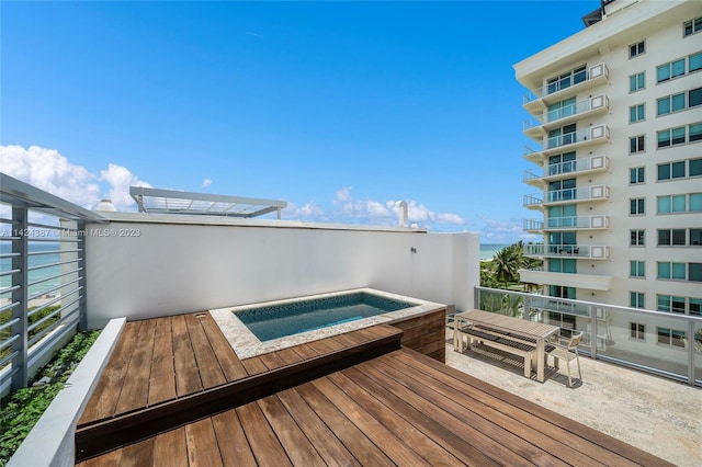 wooden deck with an in ground hot tub and a water view