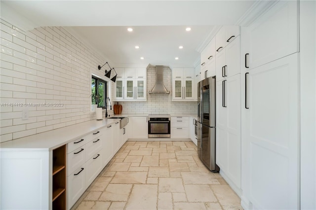 kitchen featuring stainless steel appliances, light tile patterned floors, white cabinets, tasteful backsplash, and wall chimney exhaust hood