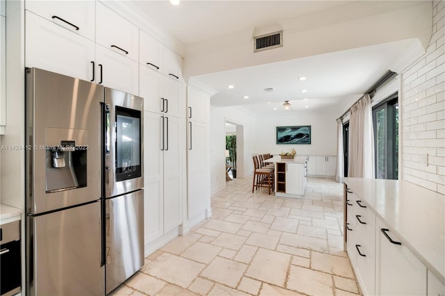 kitchen with light tile patterned flooring, white cabinets, and stainless steel fridge