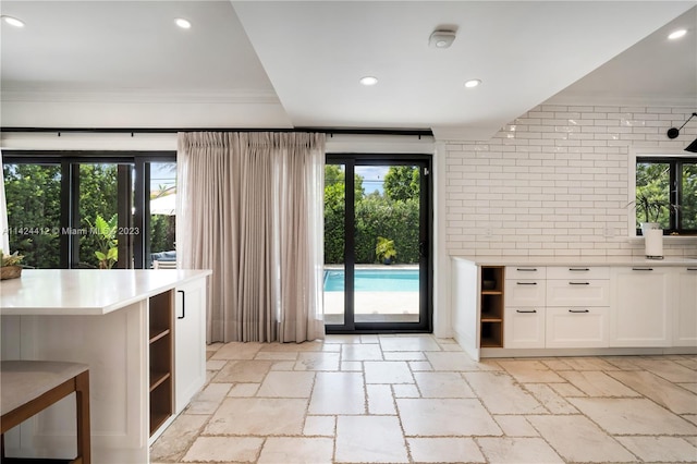 interior space with light tile patterned floors, plenty of natural light, and ornamental molding