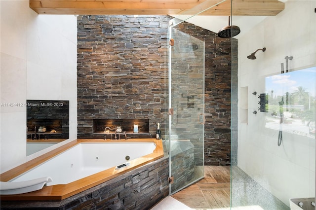 bathroom with a fireplace, tile patterned floors, a bathing tub, beamed ceiling, and tile walls