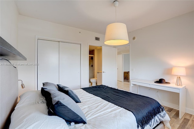 bedroom featuring connected bathroom, a closet, and light hardwood / wood-style flooring