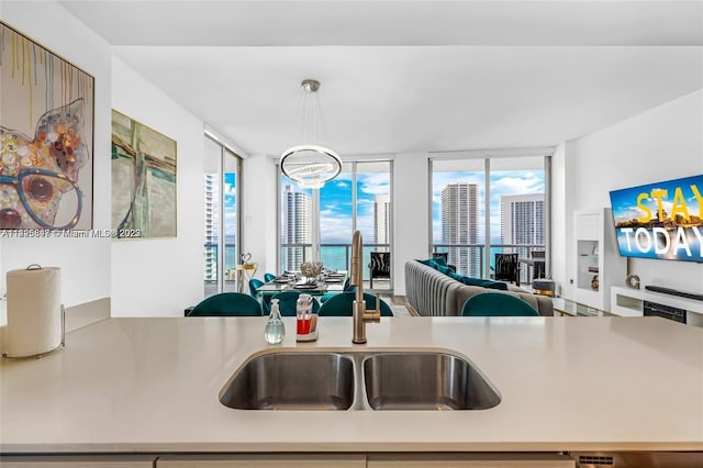 kitchen featuring decorative light fixtures, a wall of windows, sink, a water view, and a chandelier