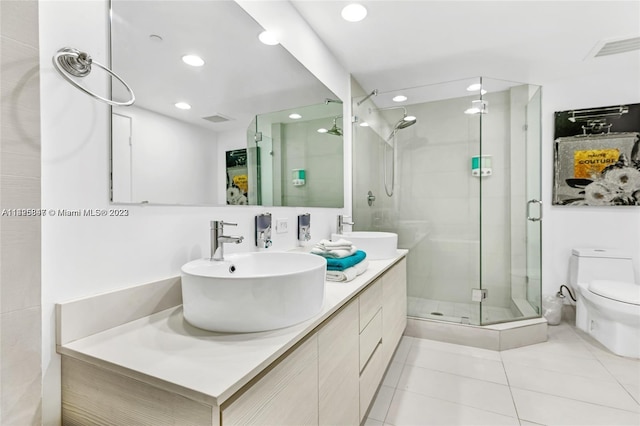 bathroom with toilet, a shower with shower door, oversized vanity, tile flooring, and dual sinks