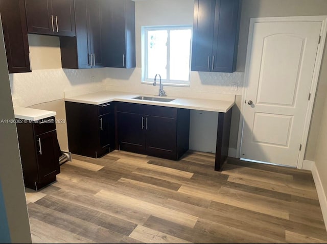 kitchen with backsplash, light hardwood / wood-style floors, and sink