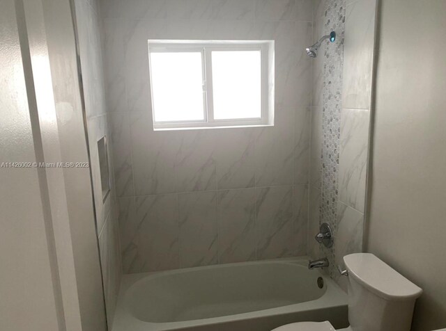 bathroom with toilet and tiled shower / bath