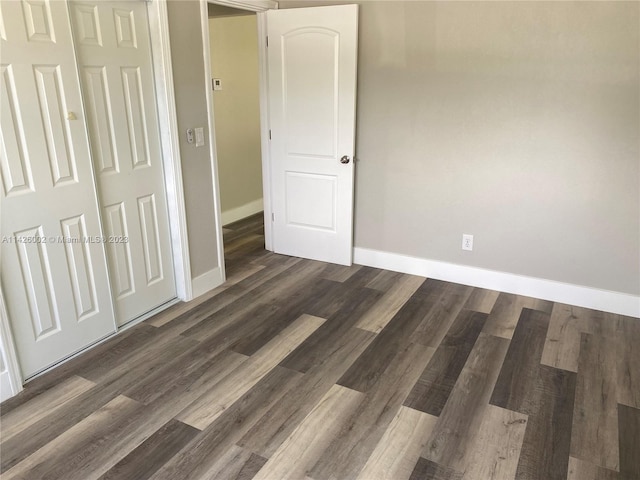 unfurnished bedroom with dark hardwood / wood-style floors and a closet