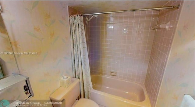 bathroom with shower / bath combination with curtain and toilet