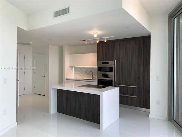 kitchen with sink, dark brown cabinets, a kitchen island, rail lighting, and stainless steel double oven