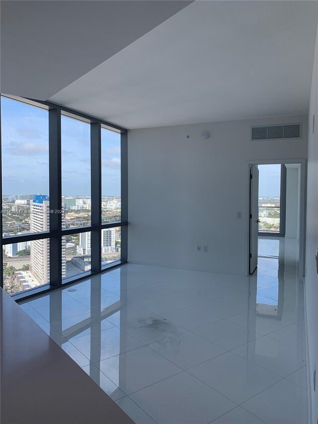 tiled empty room featuring floor to ceiling windows and a wealth of natural light