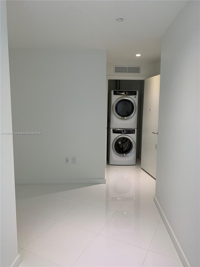 corridor featuring stacked washer and clothes dryer and light tile patterned flooring