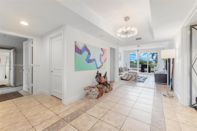 living room featuring light tile patterned floors, baseboards, visible vents, a tray ceiling, and a chandelier