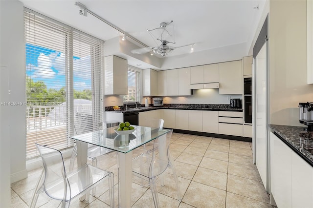 kitchen featuring light tile patterned floors, white cabinets, black dishwasher, under cabinet range hood, and modern cabinets