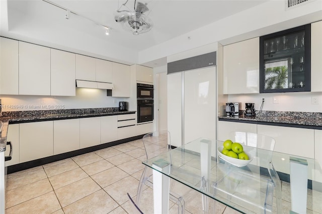 kitchen with white cabinets, light tile patterned flooring, built in refrigerator, and dobule oven black