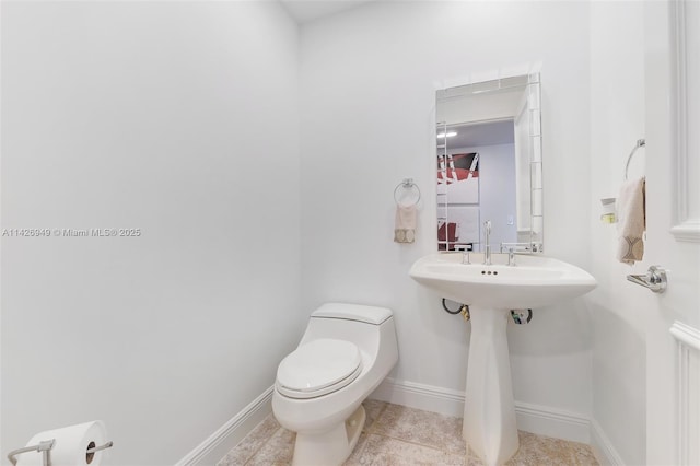 half bathroom with tile patterned floors, toilet, and baseboards