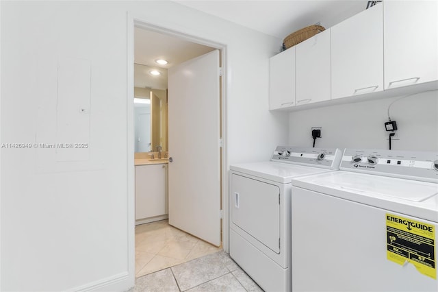 clothes washing area featuring washing machine and dryer, light tile patterned floors, cabinet space, and a sink