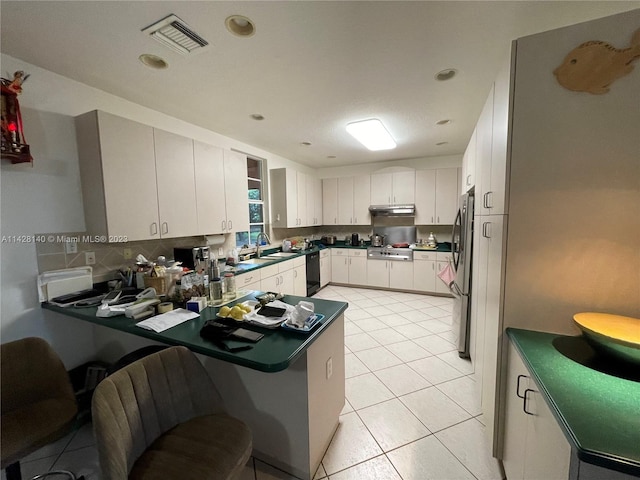 kitchen featuring sink, appliances with stainless steel finishes, backsplash, light tile flooring, and white cabinetry