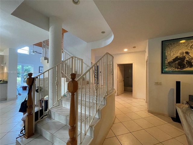 stairs featuring light tile floors and ceiling fan