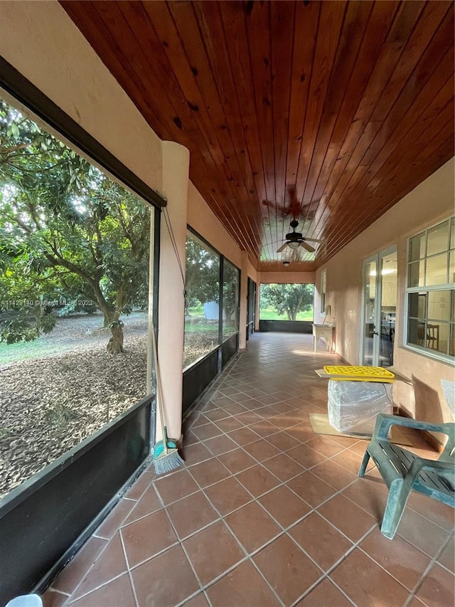 unfurnished sunroom featuring wood ceiling and ceiling fan