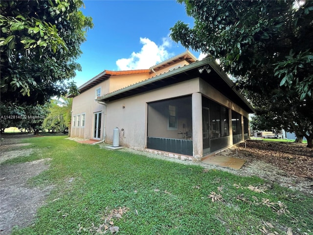 view of property exterior featuring a lawn and a sunroom