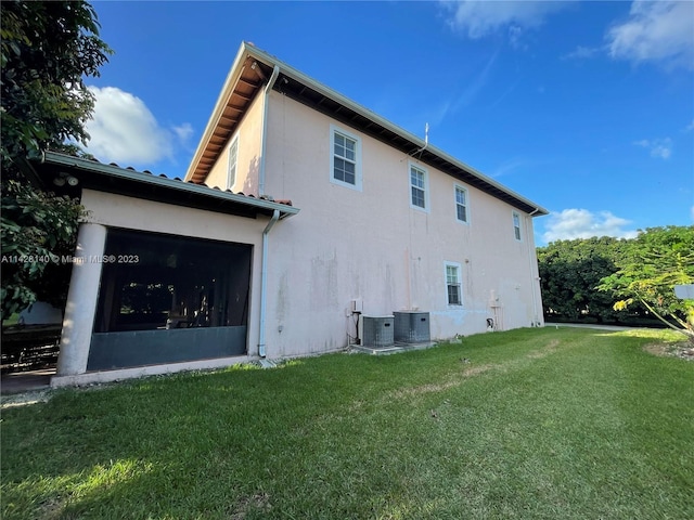 view of side of property with central AC unit and a yard