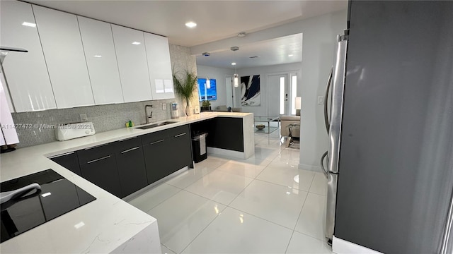 kitchen with pendant lighting, sink, light tile floors, light stone counters, and tasteful backsplash