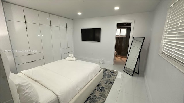 bedroom with light tile flooring and connected bathroom