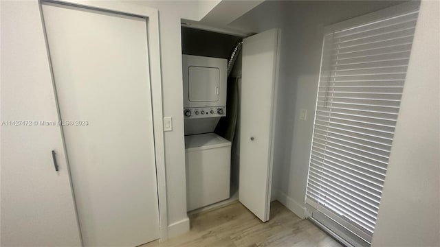 washroom with stacked washing maching and dryer and light hardwood / wood-style floors