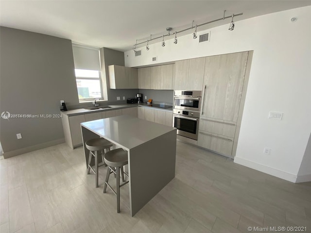 kitchen featuring a kitchen breakfast bar, light hardwood / wood-style flooring, double oven, rail lighting, and a kitchen island