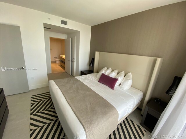 bedroom featuring light wood-type flooring and connected bathroom