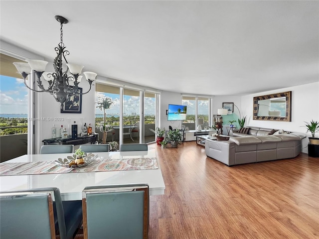 interior space with hanging light fixtures, light hardwood / wood-style flooring, floor to ceiling windows, a chandelier, and a breakfast bar area