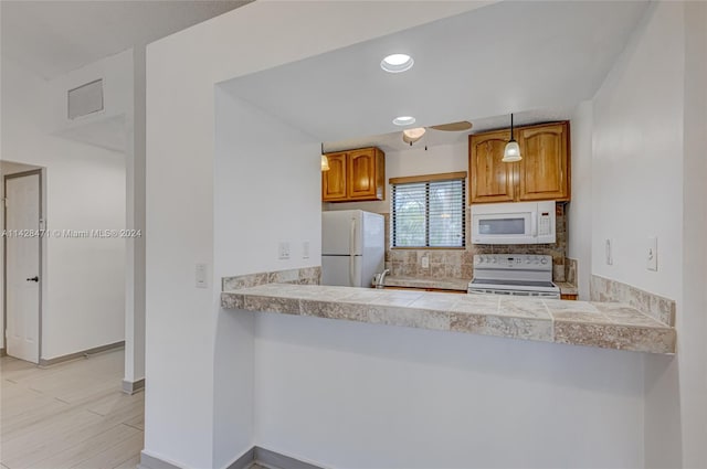 kitchen with decorative light fixtures, white appliances, and light tile floors