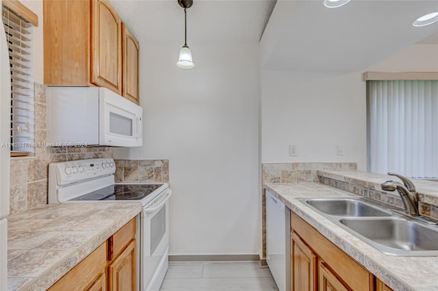 kitchen with decorative light fixtures, light tile flooring, white appliances, and sink