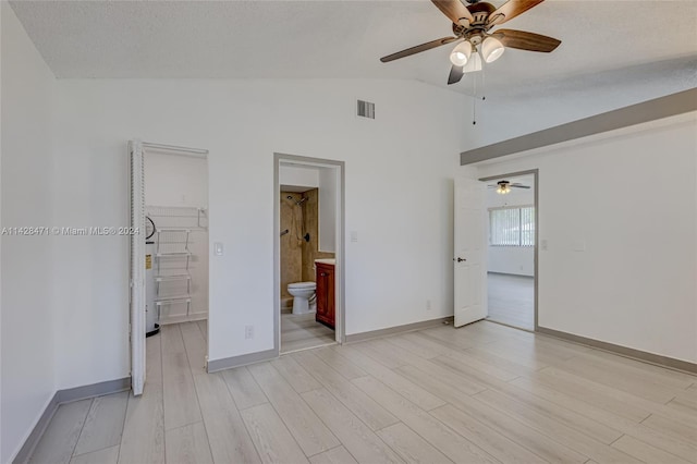 unfurnished bedroom with lofted ceiling, connected bathroom, a spacious closet, a closet, and ceiling fan