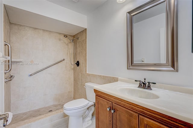 bathroom with a tile shower, vanity, and toilet