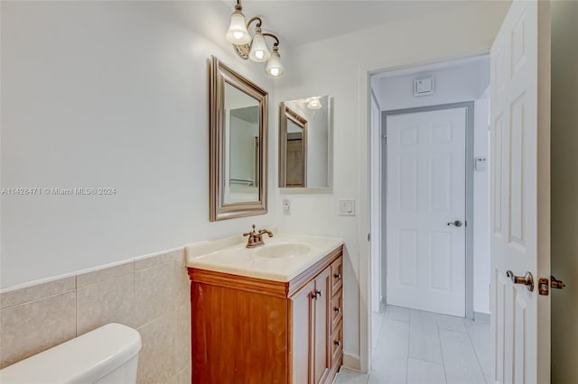 bathroom featuring tile flooring, vanity with extensive cabinet space, toilet, and tile walls