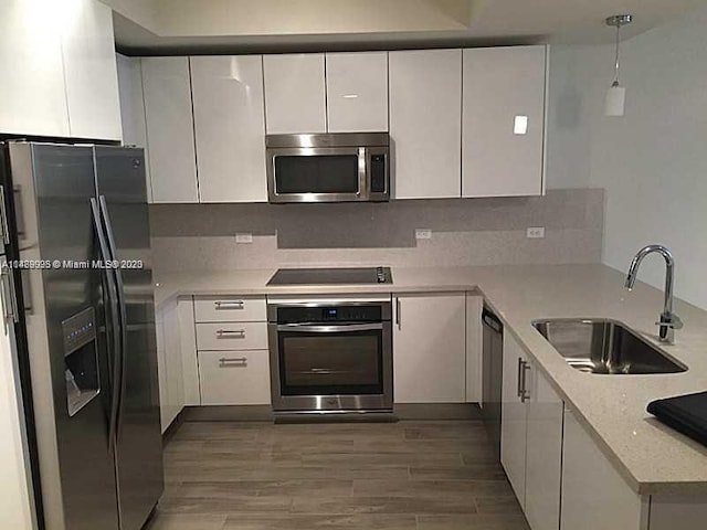 kitchen featuring light stone countertops, tasteful backsplash, black appliances, white cabinetry, and sink