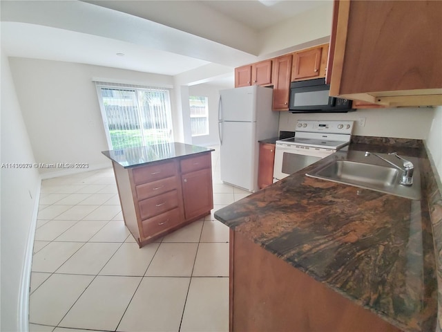 kitchen with sink, white appliances, a center island, and light tile patterned floors