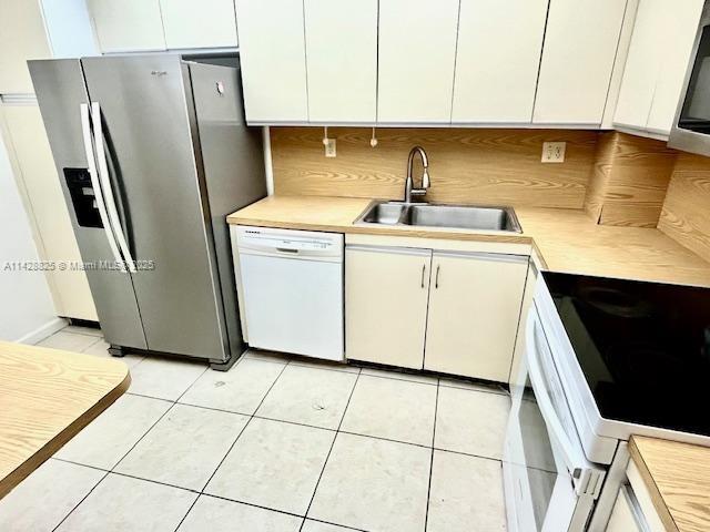 kitchen featuring light countertops, white appliances, a sink, and white cabinets