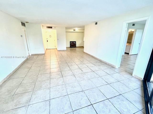 empty room with light tile patterned flooring, visible vents, and baseboards