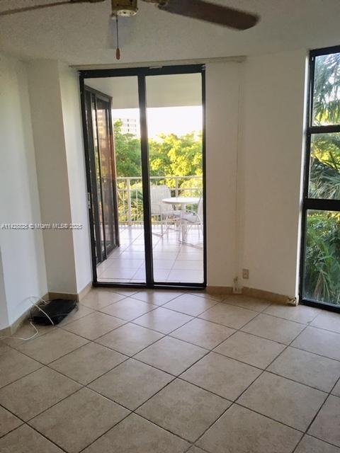 empty room with light tile patterned floors, expansive windows, and baseboards