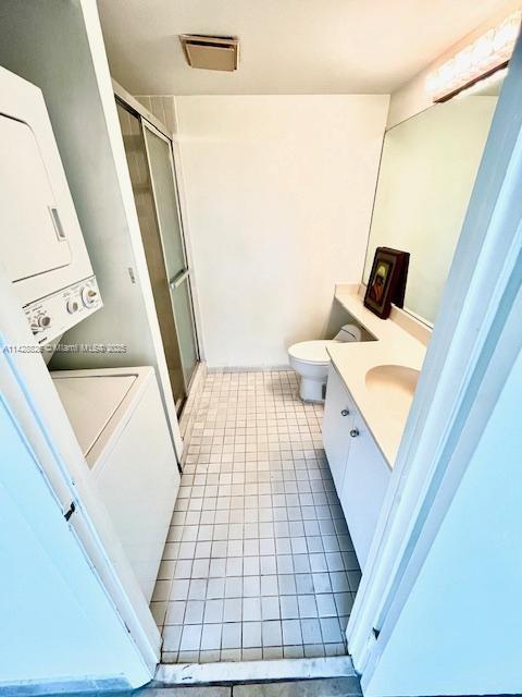 bathroom featuring tile patterned flooring, stacked washer / dryer, vanity, visible vents, and a shower stall