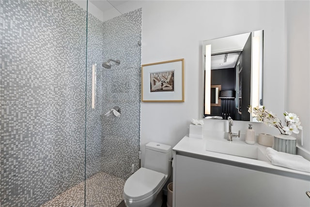 bathroom with tiled shower, vanity, and toilet