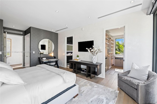 bedroom with connected bathroom and light hardwood / wood-style flooring