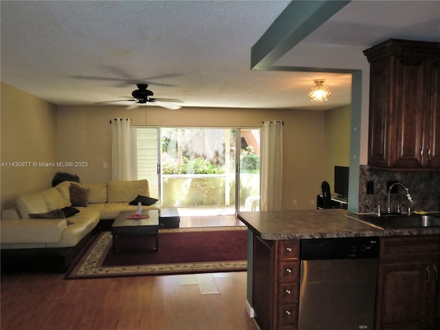 kitchen featuring a sink, dark brown cabinets, stainless steel dishwasher, backsplash, and light wood finished floors