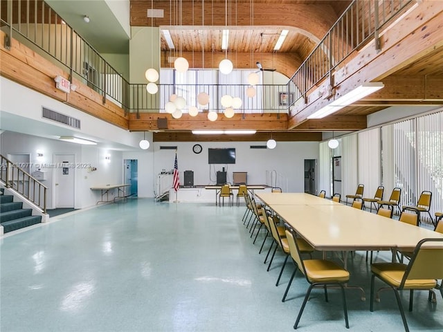 dining room with finished concrete flooring, stairway, a high ceiling, and visible vents