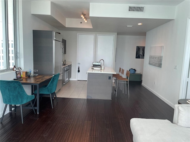 kitchen featuring light wood-type flooring, sink, stainless steel fridge, and an island with sink