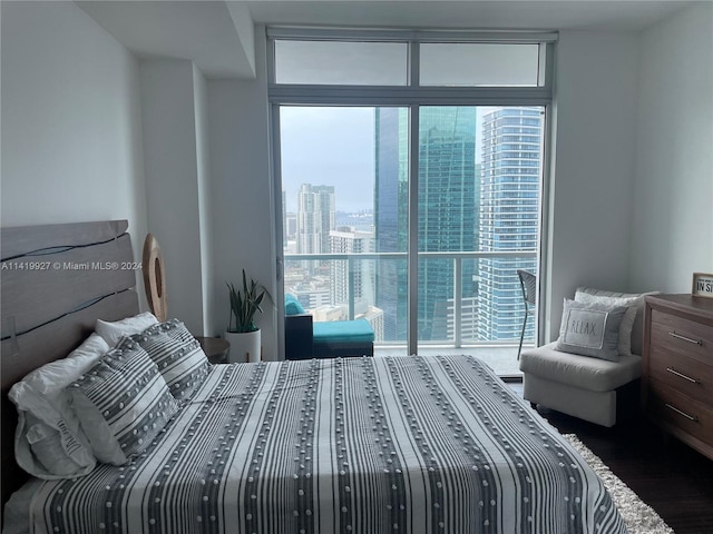 bedroom with a wall of windows and dark wood-type flooring