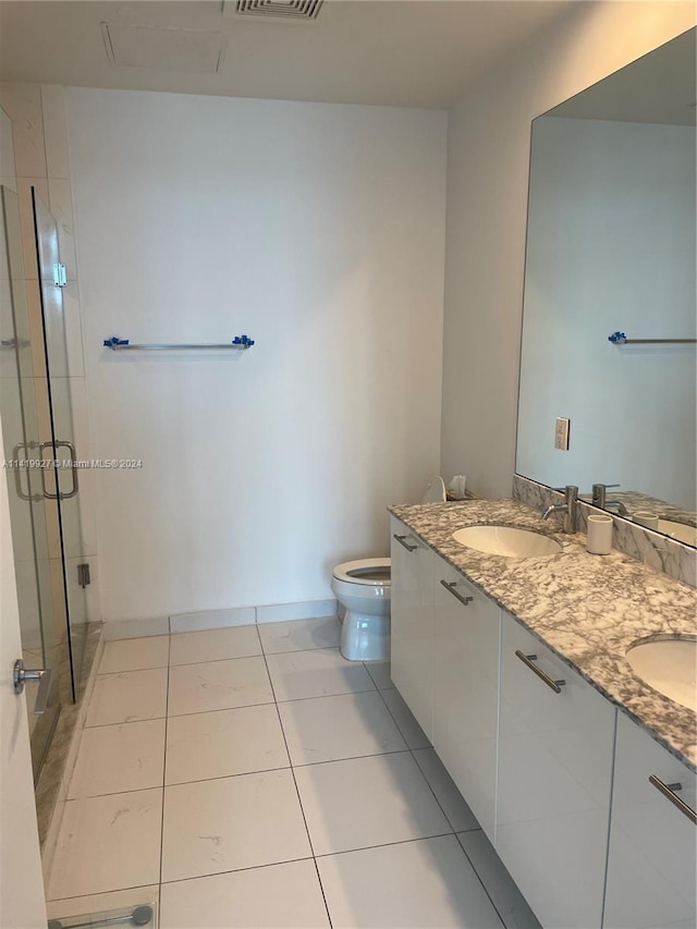 bathroom with tile patterned floors, vanity, an enclosed shower, and toilet