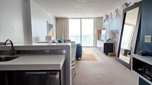 kitchen featuring light carpet, expansive windows, a textured ceiling, and sink